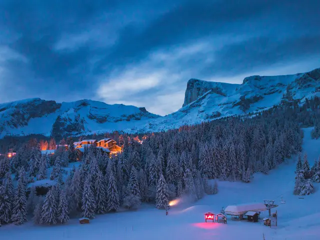 La station de ski de Superdévoluy sous la neige de nuit avec en fond le Pic de Bure, dans les Hautes-Alpes.