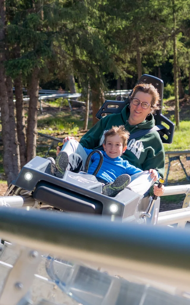 Une femme et son fils dévalent la pente sur la luge 4 saisons de Superdévoluy.