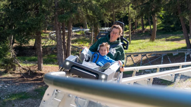 Une femme et son fils dévalent la pente sur la luge 4 saisons de Superdévoluy.